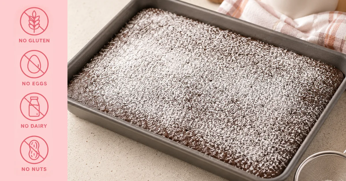 A gluten free, egg free, dairy free and nut free chocolate sheet cake dusted with icing sugar in a baking tray, next to icons for no gluten, no eggs, no dairy and no nuts