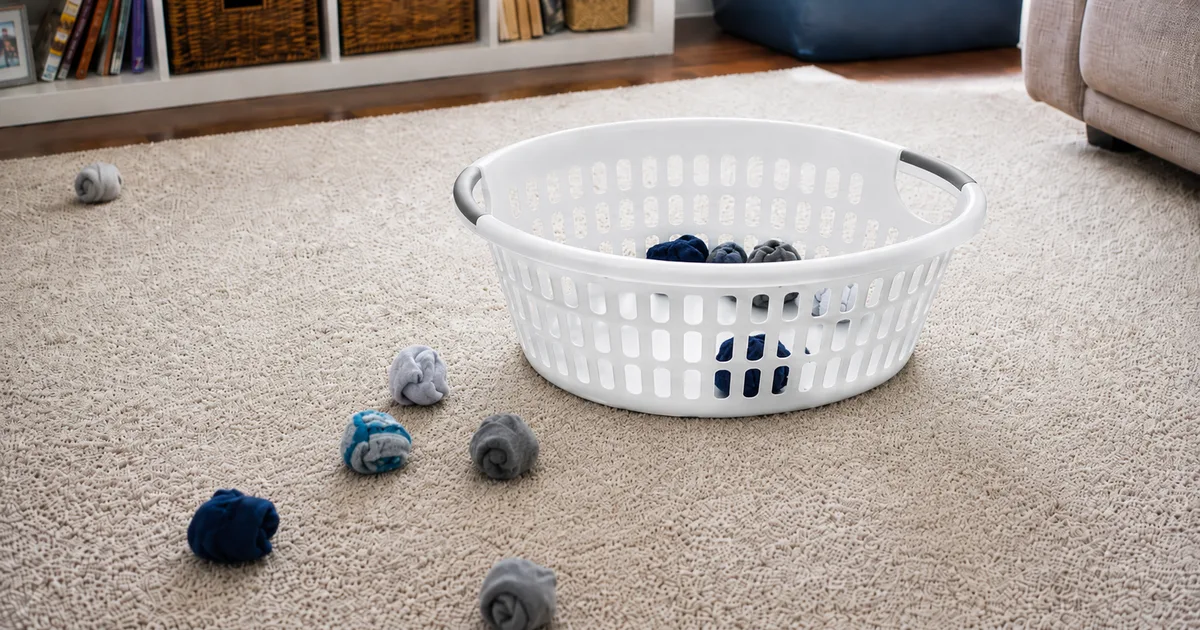 A white laundry basket on a rug surrounded by balled-up pairs of socks, mid Sock Toss game