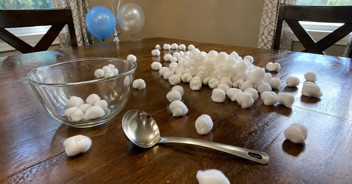 A mixing bowl and ladle set up for a blindfolded cotton ball scoop game